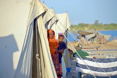 A displaced flood-affected woman stands with her child at a makeshift camp alongside flood waters in Jaffarabad district of Balochistan province on October 5, 2022.   AFP