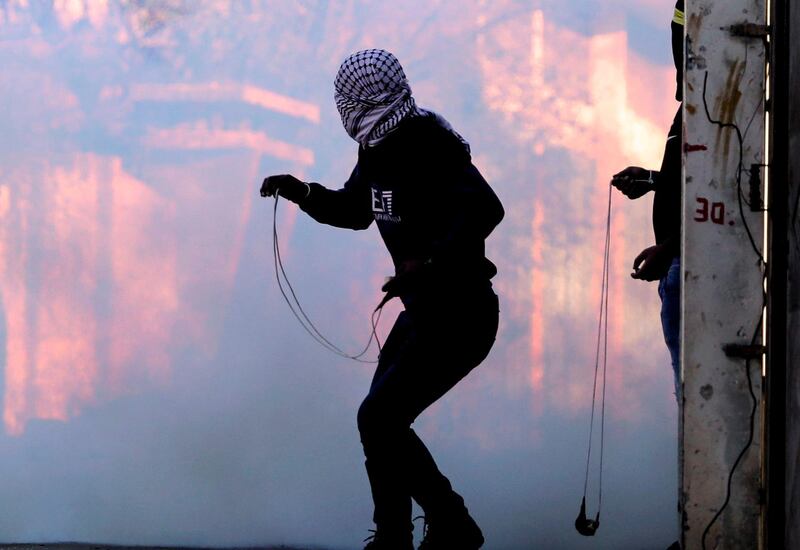 Palestinian protesters hurl stones at Israeli troops using slingshots during clashes  with Israeli troops following a demonstration against the expropriation of Palestinian land by Israel, in the village of Kfar Qaddum near the Jewish settlement of Qadumim (Kedumim), in the Israeli-occupied West Bank, on December 19, 2020. / AFP / JAAFAR ASHTIYEH
