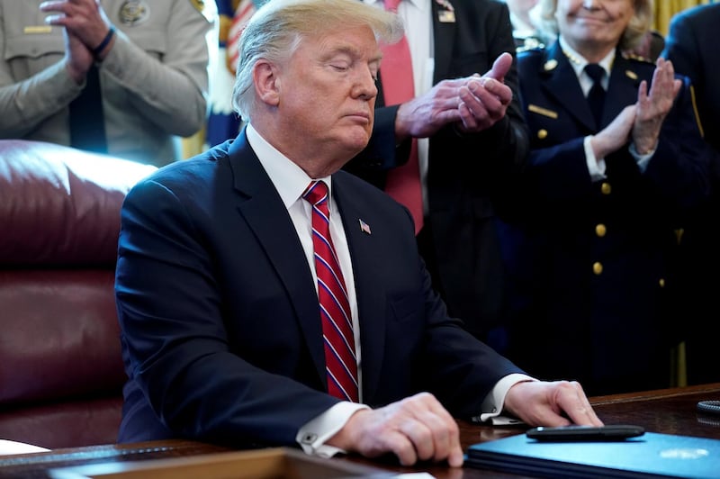 FILE PHOTO: President Donald Trump looks at his veto of the congressional resolution to end his emergency declaration to get funds for a border wall after signing it during a ceremony in the Oval Office of the White House in Washington, U.S., March 15, 2019. REUTERS/Jonathan Ernst/File Photo