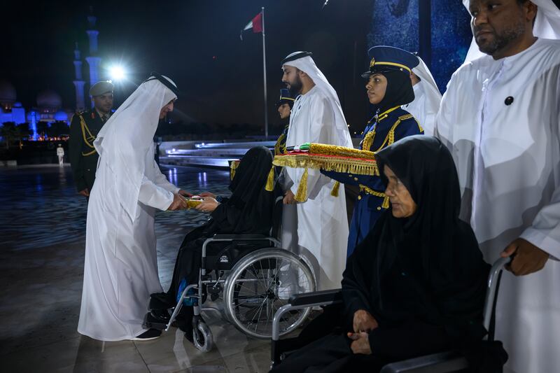 Sheikh Saud presents a medal to a family member of a martyr.