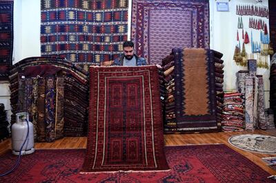 In this picture taken on January 18, 2021, Abdul Wahab, a tribal carpet collector displays a rug during an interview with AFP inside his shop at Chicken Street in Kabul. Rug hunters can spend weeks -- if not months -- passing through villages like sleuths along old caravan trails, offering cash or bartering with modern goods to amass a diverse selection of pieces they can later peddle in rug bazaars or to collectors. - TO GO WITH AFGHANISTAN-RUGS-CONFLICT,FEATURE BY DAVID STOUT
 / AFP / WAKIL KOHSAR / TO GO WITH AFGHANISTAN-RUGS-CONFLICT,FEATURE BY DAVID STOUT
