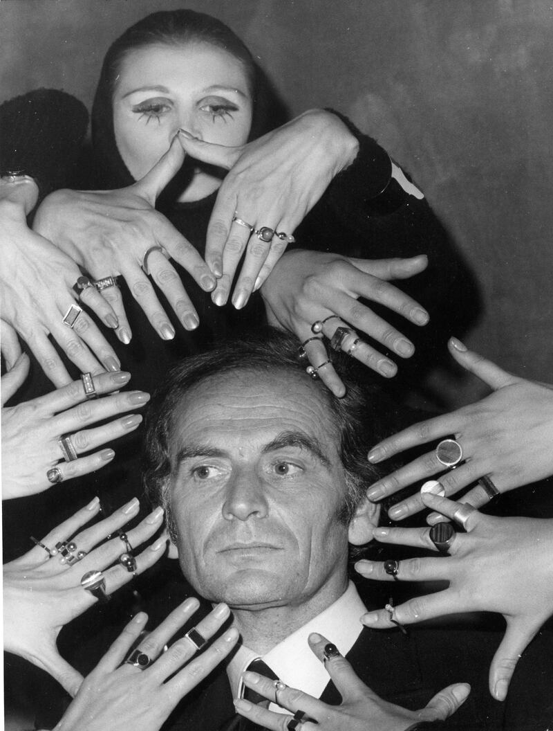 Pierre Cardin surrounded by models's hands, in 1969. AP