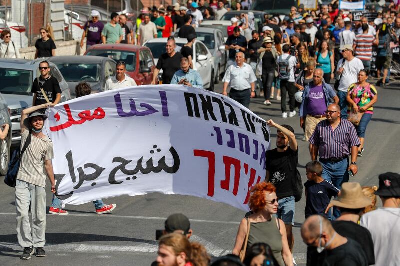 Demonstrators in East Jerusalem carry a banner that reads: " We are with you Sheikh Jarrah." AFP
