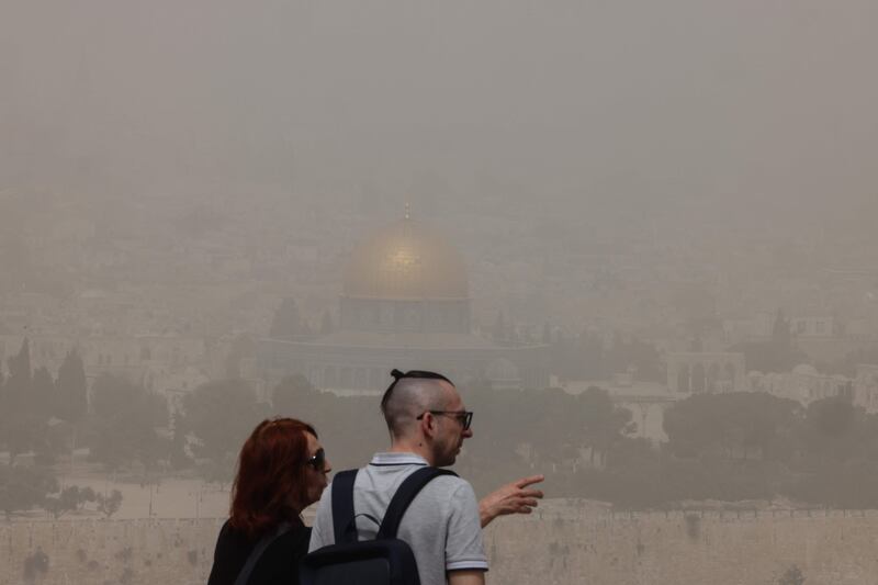 People visiting the Mount of Olives gaze at a view of Jerusalem's Old City during a dust storm,  April 24, 2022.  AFP