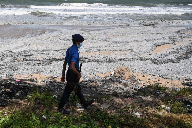 A Sri Lanka Navy officer patrols the shore as he walks through the washed up debris. AFP