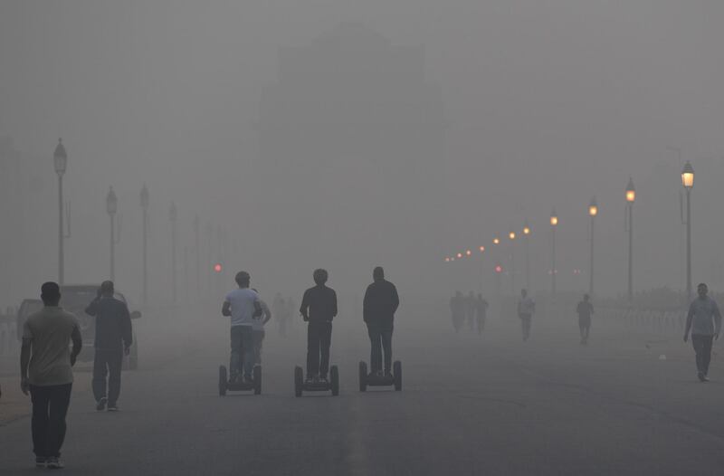 Indian pedestrians make their way down the street near the India Gate monument amid heavy smog conditions in New Delhi.  AFP