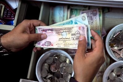 A store cashier receives payment from a customer on Tuesday, Nov. 8, 2011, at a local convenience store in Abu Dhabi. (Silvia Razgova/The National)
 currency dirham dirhams