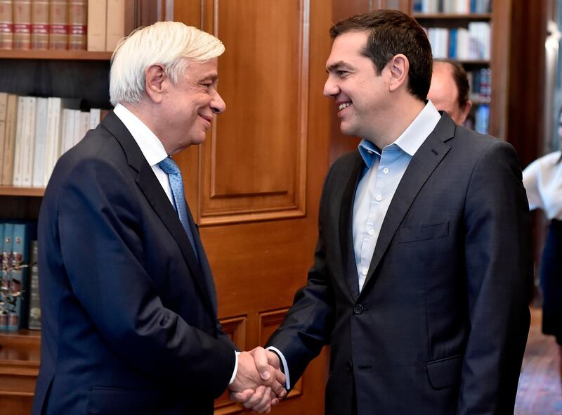 Greek President Prokopis Pavlopoulos (L) shakes hands with Greek Prime Minister Alexis Tsipras at the Presidential Palace in Athens on June 22, 2018, following a decision by Eurozone financial ministers to complete the eight-year bailout program for Greece.  Greek Prime Minister Alexis Tsipras said the country was "turning a page" after eurozone ministers declared its crisis over as they granted Athens debt relief under a bailout exit strategy. / AFP / Milos Bicanski
