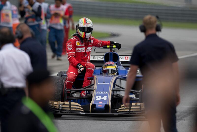 Ferrari driver Sebastian Vettel of Germany returns to the pit area with a ride from Sauber driver Pascal Wehrlein of Germany after the Malaysian Formula One Grand Prix in Sepang, Malaysia, Sunday, Oct. 1, 2017. (AP Photo/Thomas Lam)