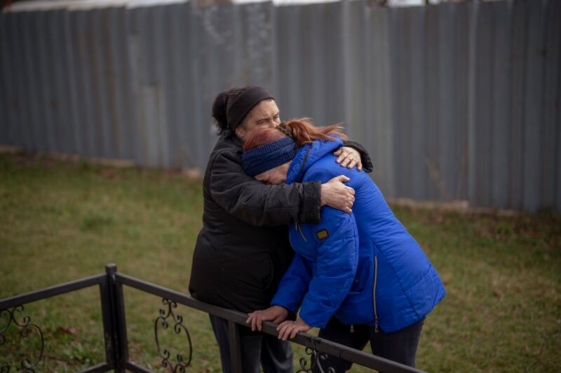 Ira Slepchenko, 54, and Valya Naumenko, 47, embrace as they  mourn the deaths of their husbands, at the exhumation of a mass grave in Bucha, near Kyiv. AP