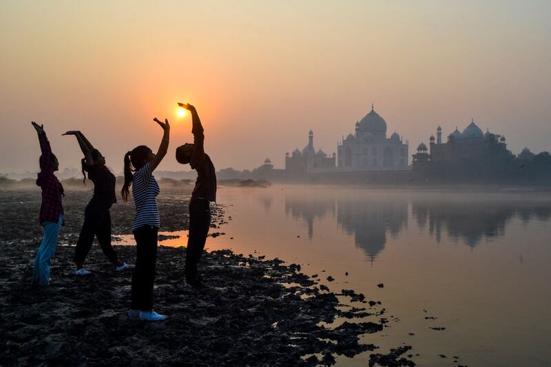 Children exercise on the banks of the Yamuna River near the Taj Mahal in Agra at sunrise. AFP