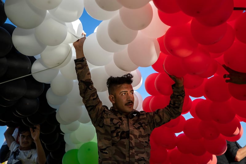 A supporter of President Bashar Al Assad prepares to release hundreds of balloons in the colours of the Syrian flag, at Umayyad Square, Damascus. Presidential elections are being held on Wednesday. AP Photo