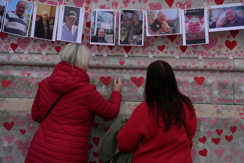 Family members write a message to two sisters who died of Covid-19 on the National Covid Memorial wall. AP Photo