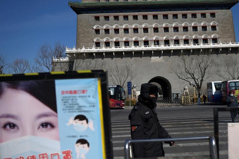 A security guard wearing a face mask walks past a poster promoting mask-wearing near the Qianmen pedestrian street, following an outbreak of the novel coronavirus in the country, in Beijing, China. REUTERS