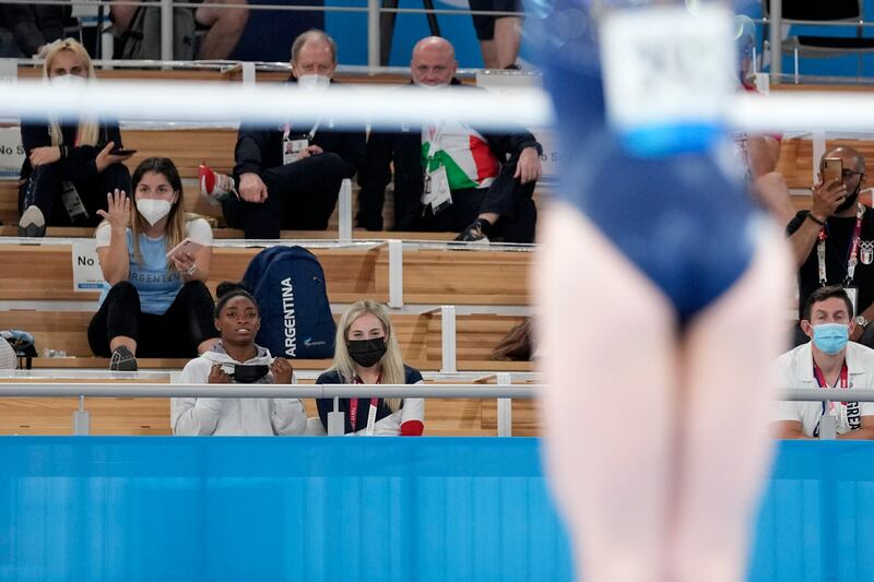 Simone Biles, of the United States, watches the performance of teammate Jade Carey on the uneven bars during the artistic gymnastics women's all-around final.