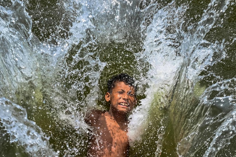 A child takes a dip in a lake to get respite from the heat on a summer afternoon in Dhaka. AFP