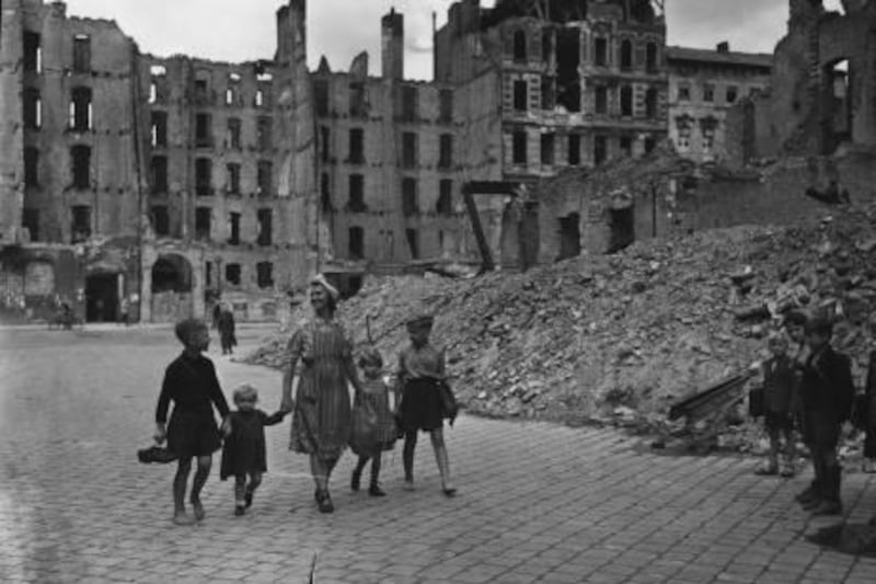 October 1945:  Elsa Gabriele passes by the battle ruins of Berlin as she accompanies her family to school.The boys carry their shoes to save on wear and tear.  (Photo by Fred Ramage/Keystone Features/Getty Images)