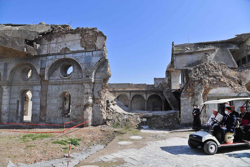 Pope Francis rides in a golf cart at the ruins of the Syriac Catholic Church of the Immaculate Conception. AFP