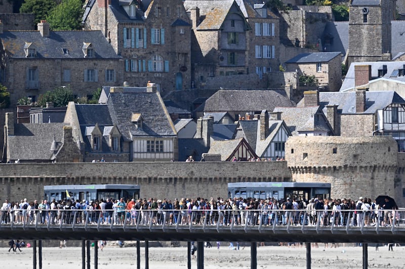 Tourists stand in line to catch buses and reach parking lots as they leave the site of Le Mont-Saint-Michel, northwestern France, on July 25. AFP