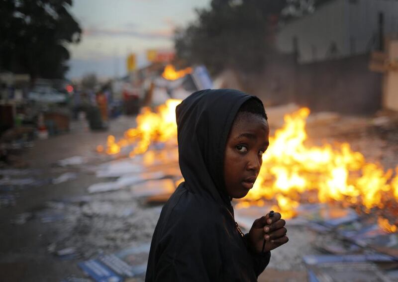 A young boy walks past a burning fire used to keep evicted families warm overnight after police and private security evicted families from a commercial property in Johannesburg, South Africa. Kim Ludbrook / EPA