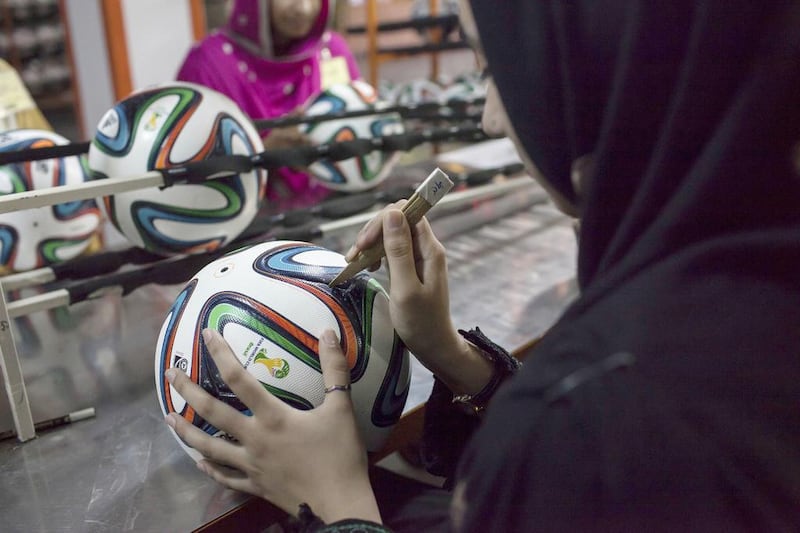 An employee conducts the final check to fix any cavity in the seams of a ball inside the football factory. Sara Farid / Reuters

