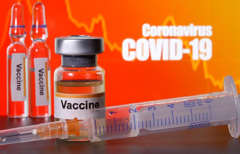Small bottles labeled with "Vaccine" stickers stand near a medical syringe in front of displayed "Coronavirus COVID-19" words in this illustration taken April 10, 2020. REUTERS/Dado Ruvic/Illustration