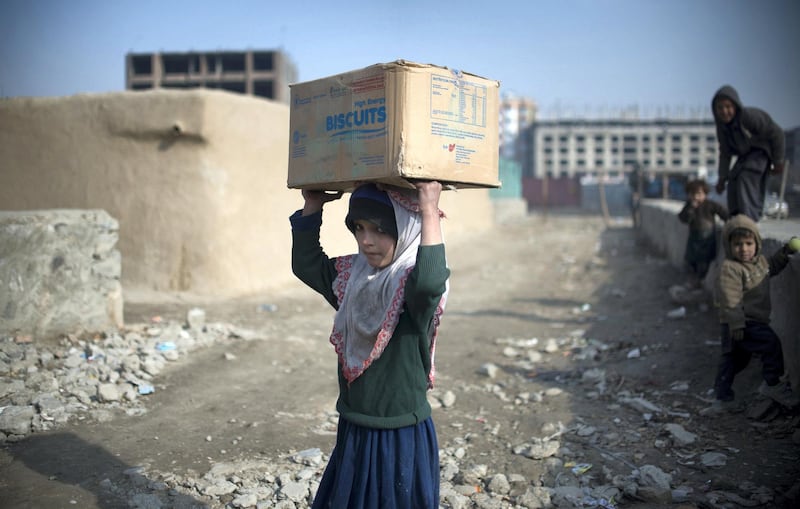 Afghan girl, Habiba carries a box of high energy biscuits received from the World Food Programme (WFP) to her home in a refugee camp in Kabul on January 26, 2014.  Economic development is considered a vital weapon to stop the country from sinking back into civil war and to stem Islamist extremism after 100,000 international combat troops pull out.  AFP PHOTO/JOHANNES EISELE / AFP PHOTO / JOHANNES EISELE
