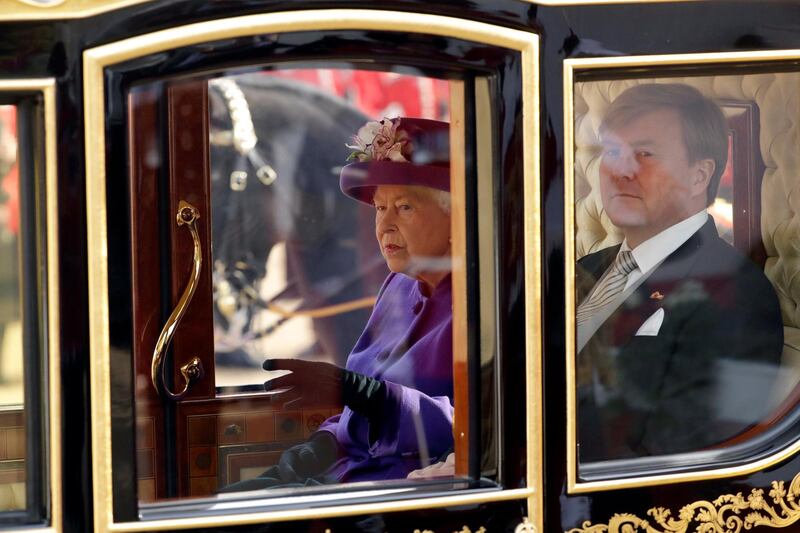 Britain's Queen Elizabeth and King Willem-Alexander of the Netherlands leave in a horse-drawn carriage after a ceremonial welcome during a state visit. Matt Dunham / AFP