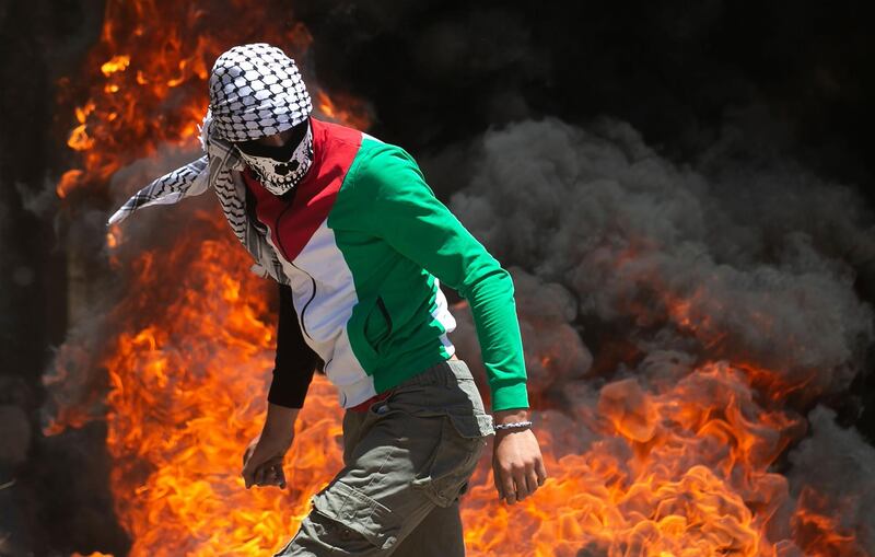 A Palestinian protester walks near burning tyres during clashes with Israeli forces during a demonstration in the village of Kfar Qaddum in the Israeli-occupied West Bank. AFP