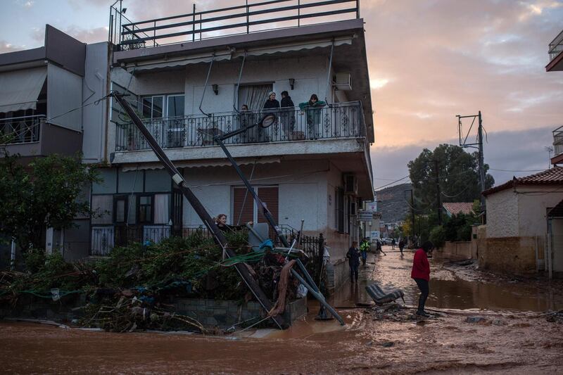 A person walks past debris and a downed power line in a flooded street in the town of Mandra, northwest of Athens, on November 15, 2017, after heavy overnight rainfall in the area caused damage and left seven people dead. 
At least seven people died on November 15 and more were missing after a strong overnight downpour flooded three towns in Greece, officials said. The flooding struck the towns of Mandra, Nea Peramos and Megara, a semi-rural area west of Athens where many factories and warehouses are based. / AFP PHOTO / Angelos Tzortzinis