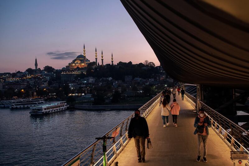 Backdropped by the Suleymaniye Mosque, people wearing protective masks to help prevent the spread of the coronavirus walk a on the Golden Horn Bridge, over the Golden Horn, in Istanbul. Turkey's interior ministry has banned smoking in public places, including parks, across the country to curb the spread of COVID-19. AP Photo