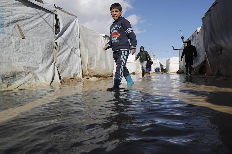 A child wades through rain and snow waters at an informal tent settlement housing Syrian refugees following winter storms in the area of Delhamiyeh, in the central Bekaa Valley on January 17, 2019. Lebanon plays host to over one million Syrian refugees who fled as neighbouring Syrian fell into civil war at the start of March 2011.  / AFP / JOSEPH EID
