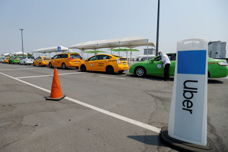 Taxis line up next to an Uber pick-up area along with Uber and Lyft drivers. Reuters