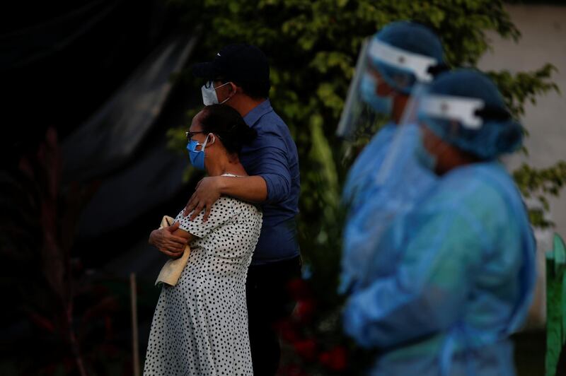 Cemetery workers stand near relatives who attended to the burial of a man, who died of the coronavirus disease, at the Cementerio Jardin cemetery in Soyapango, El Salvador. Reuters