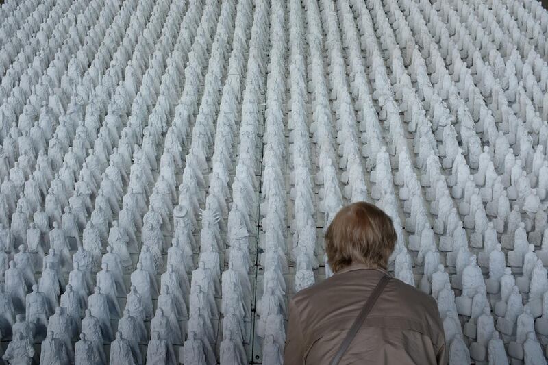 A visitor looks at 1,120 clay figures, each approximately 30cm tall, of the work "Transit" by Georg Korner at an art fair at the former Tempelhof Airport,  Berlin, Germany. Getty