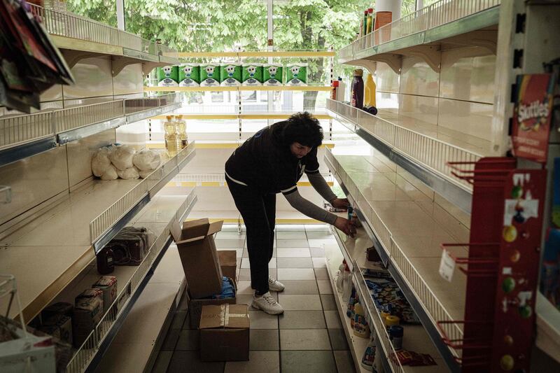 A shopkeeper clears shelves before closing up in Sviatohirsk, eastern Ukraine, amid the Russian invasion. AFP