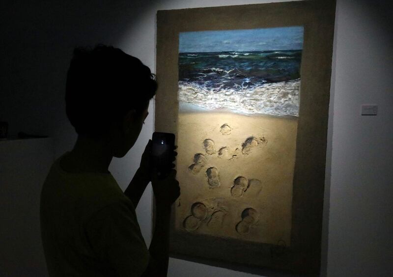 A Libyan boy takes a picture with his smartphone of a painting by local artist Elham el-Ferjani at the Hamim Gallery in the eastern Libyan city of Benghazi. The city is hosting a rare week of culture featuring theatre, music, cinema and art. AFP