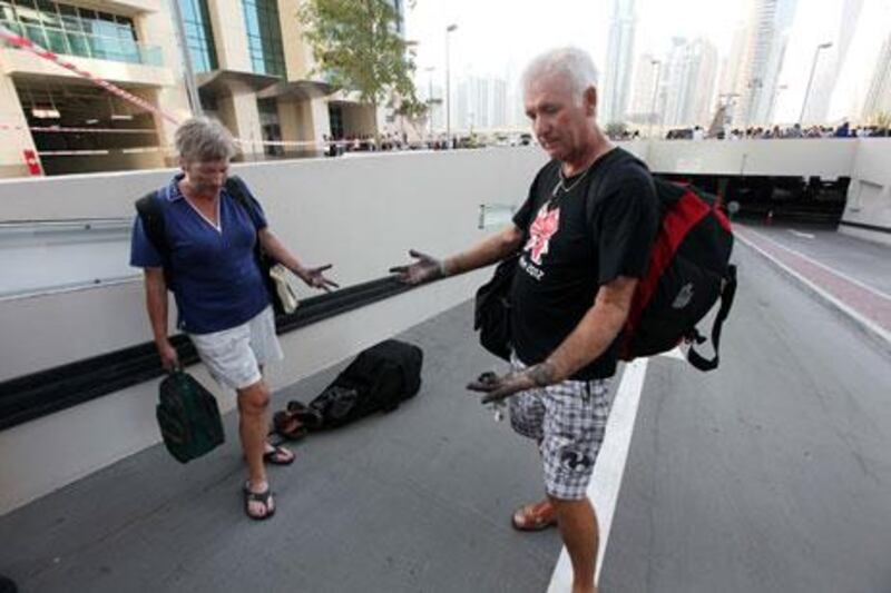 Jim Bishop and Jane Bishop come out with their belongings from Tamweel Tower in Jumeirah Lakes Towers.