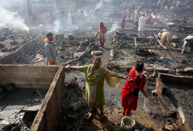 A woman griefs while she and others collect their belongings in Karachi, Pakistan, Saturday, Nov.  20, 2021, following a fire that gutted hut homes.  Scores of huts were burnt to ashes as the fire erupted making dozens of families homeless in a slum of Karachi, local media reported.  (AP Photo / Fareed Khan)