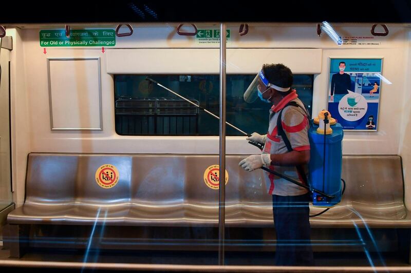 A Delhi Metro rail employee sanitises a coach during a media preview as the Delhi Metro network prepares to resume services partially after shutting down for more than five months because of the pandemic, at Rajeev Chowk metro station in New Delhi.  AFP