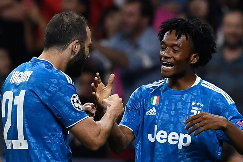 Juventus' Colombian midfielder Juan Cuadrado is congratulated by teammate Gonzalo Higuain after scoring the opening goal against Atletico Madrid at The Wanda Metropolitano Stadium in Madrid. The Champions League Group D match ended 2-2. AFP