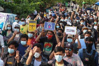 Demonstrators carry placards and flash the three-finger salute during an anti-military coup protest yesterday in Mandalay, Myanmar. EPA