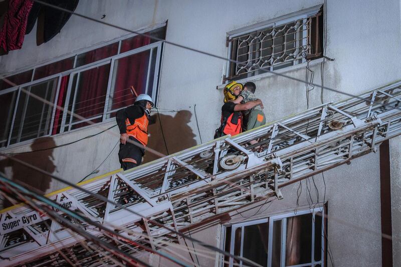 Firefighters move families from a building whose entrance was blocked by rubble after Israeli air strikes on Gaza City. AFP