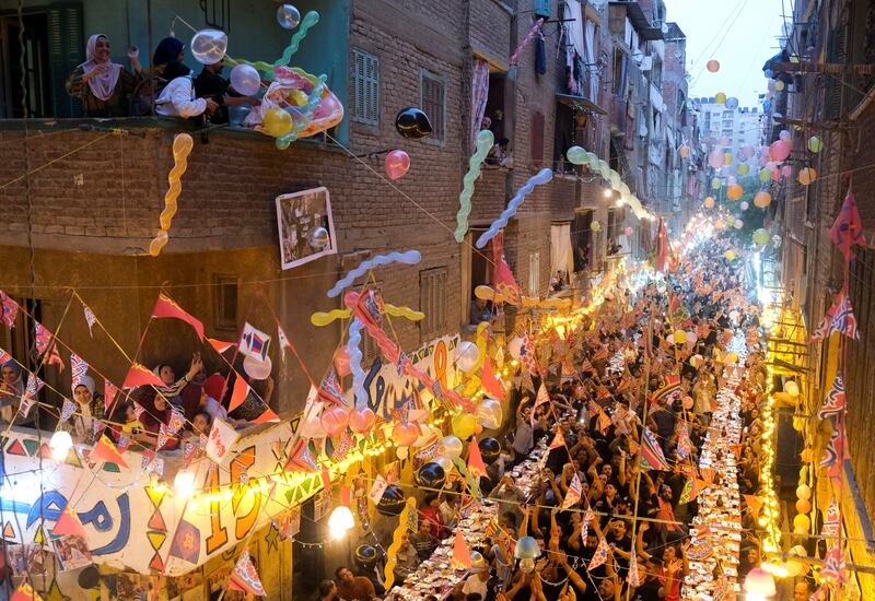 Residents sit back-to-back along two tables running down a narrow street festooned with balloons, bunting and banners as they enjoyed a meal of barbecued meat, rice and pickles.