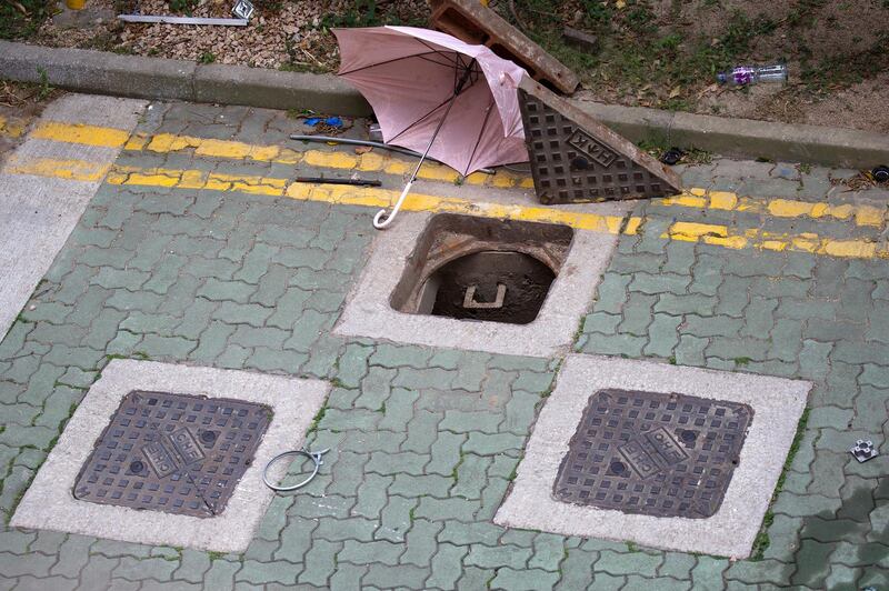 A broken umbrella lies next to the manholes at the Hong Kong Polytechnic University which protesters has tried to use it to escape. AP Photo