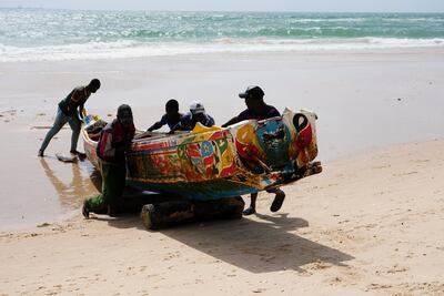 Men push a pirogue on the beach in Saint Louis, Senegal. AP 