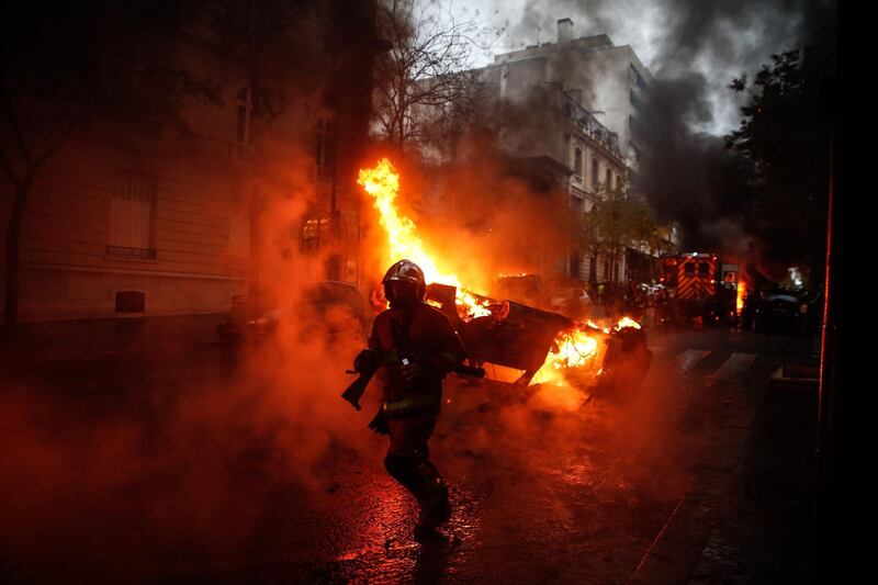 Firemen at work to extinguish a burning car on the sideline of a demonstration in Paris. AFP