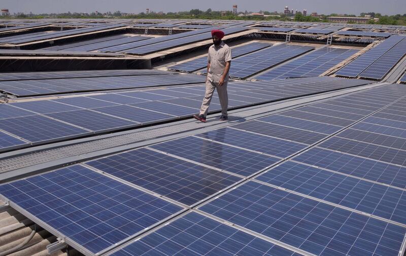 An Indian security personnel poses for media as he walks over rooftops covered in solar panels at the Solar Photovoltaic Power Plant, some 45kms from Amritsar on May 17, 2016. 
Spread over eight rooftops, the solar panels cover some 82 acres. / AFP PHOTO / NARINDER NANU