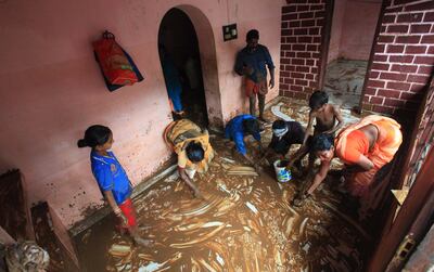 People clear mud and slush from their flood-hit house following heavy rain in Kottayam district of Kerala, India. EPA