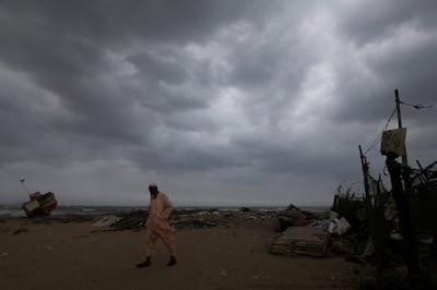 Amjad Khan, 48, a boat maker, walks as rain clouds gather in the background, before the arrival of cyclonic storm Biparjoy, in Karachi.  Reuters